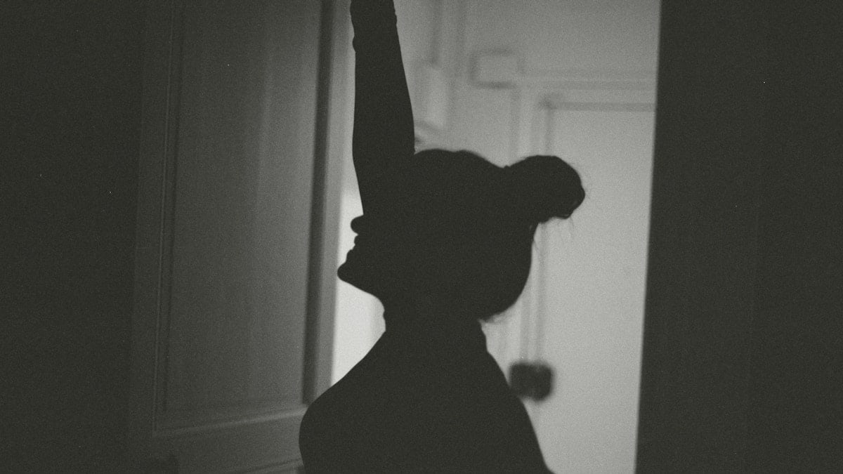 A person standing in a doorway with their arm up